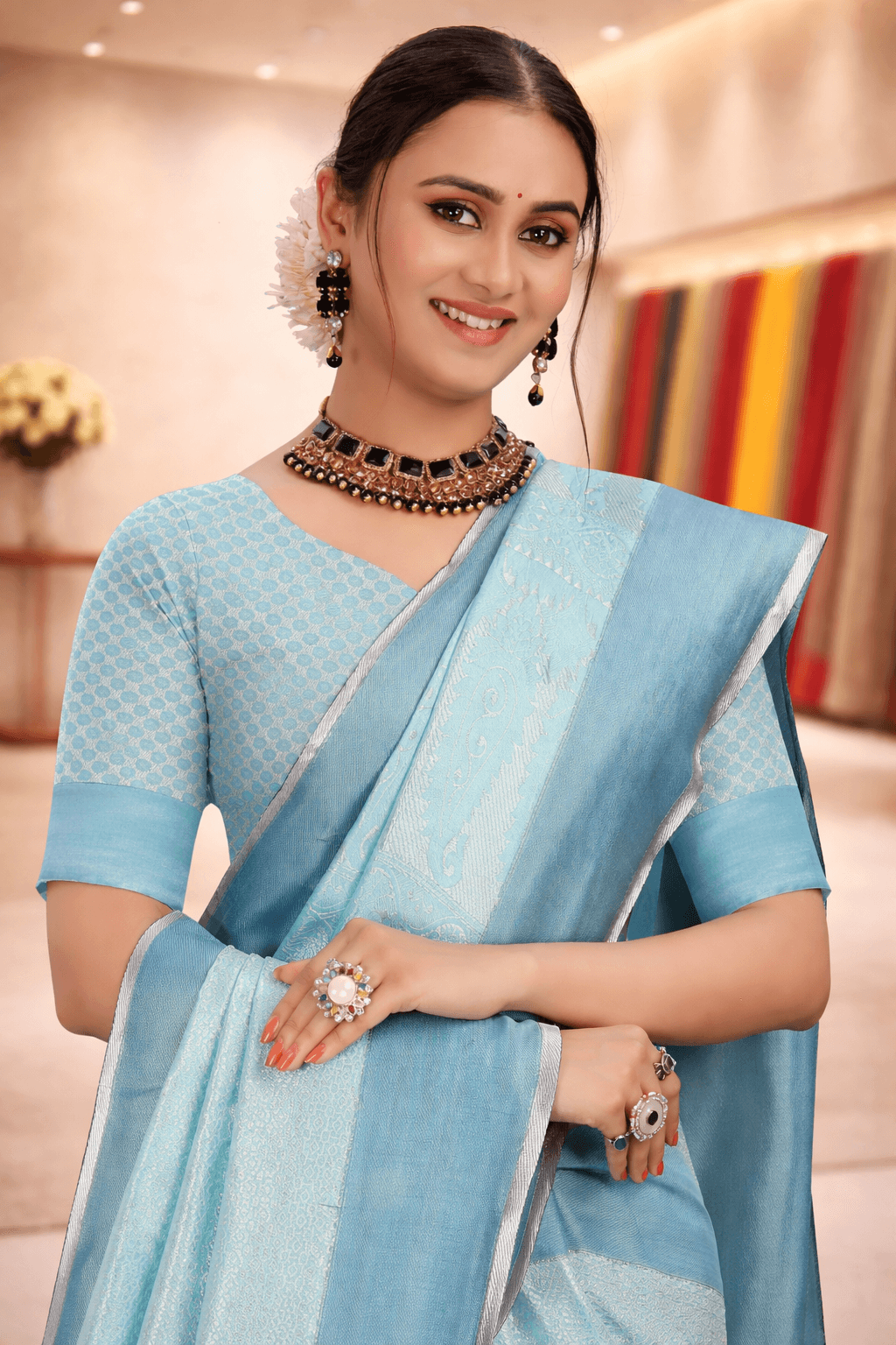 Close-up of a smiling woman wearing a pastel firozi blue woven silk saree with matching jewelry