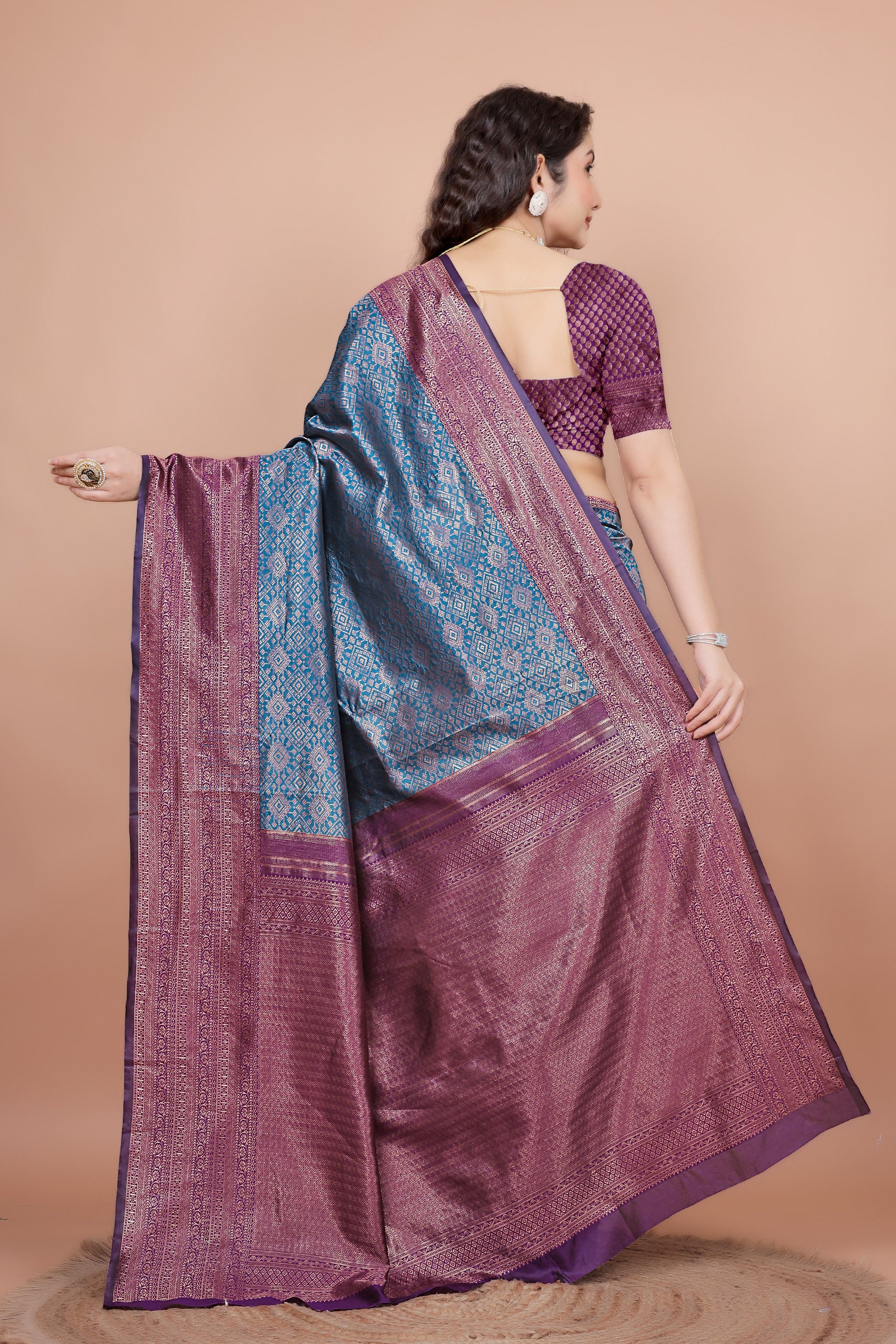 Back view highlighting the textured wine blouse and the flowing woven zari pallu