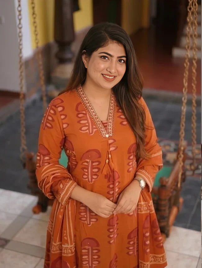 Close-up of a smiling model showcasing the elegant V-neckline with intricate embroidery on a rust orange printed cotton kurta.