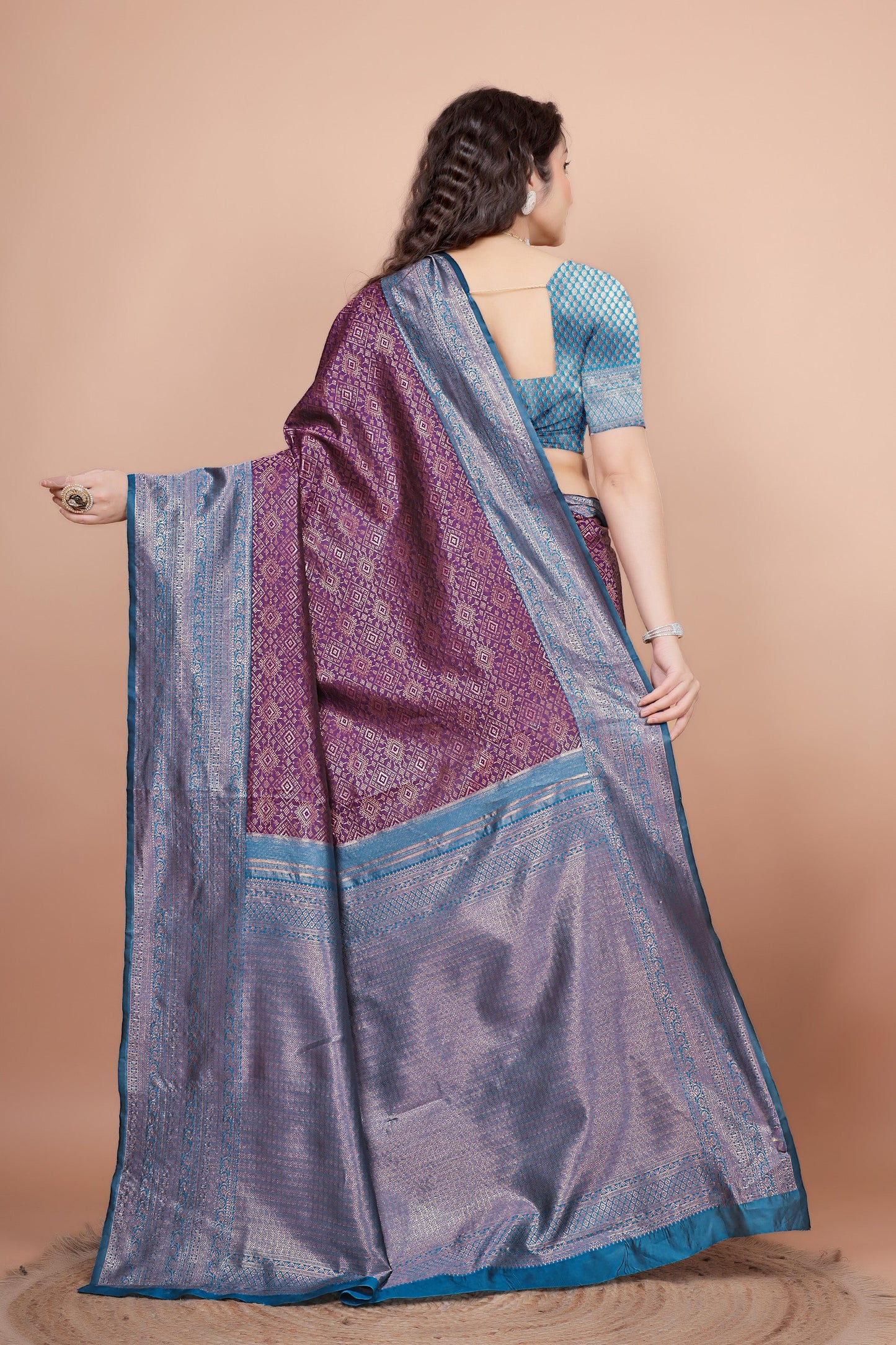 Back view highlighting the textured peacock blue blouse and the flowing woven zari pallu